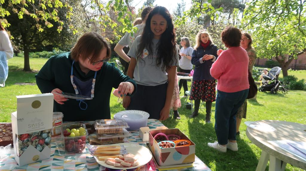 Two people looking at food spread on a table in a garden