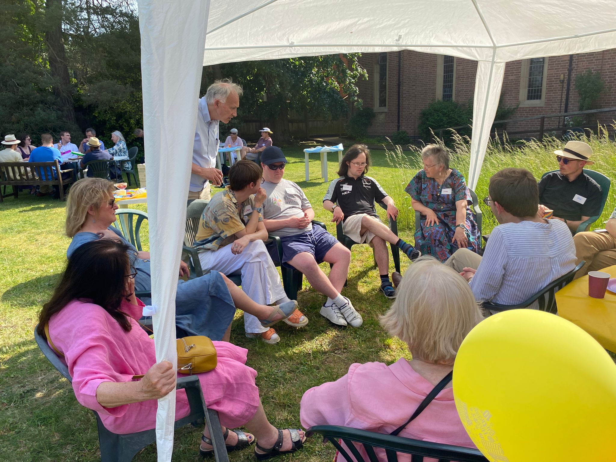 Poeple at Lyn's House's 10-year anniversary seated outdoors under a gazebo