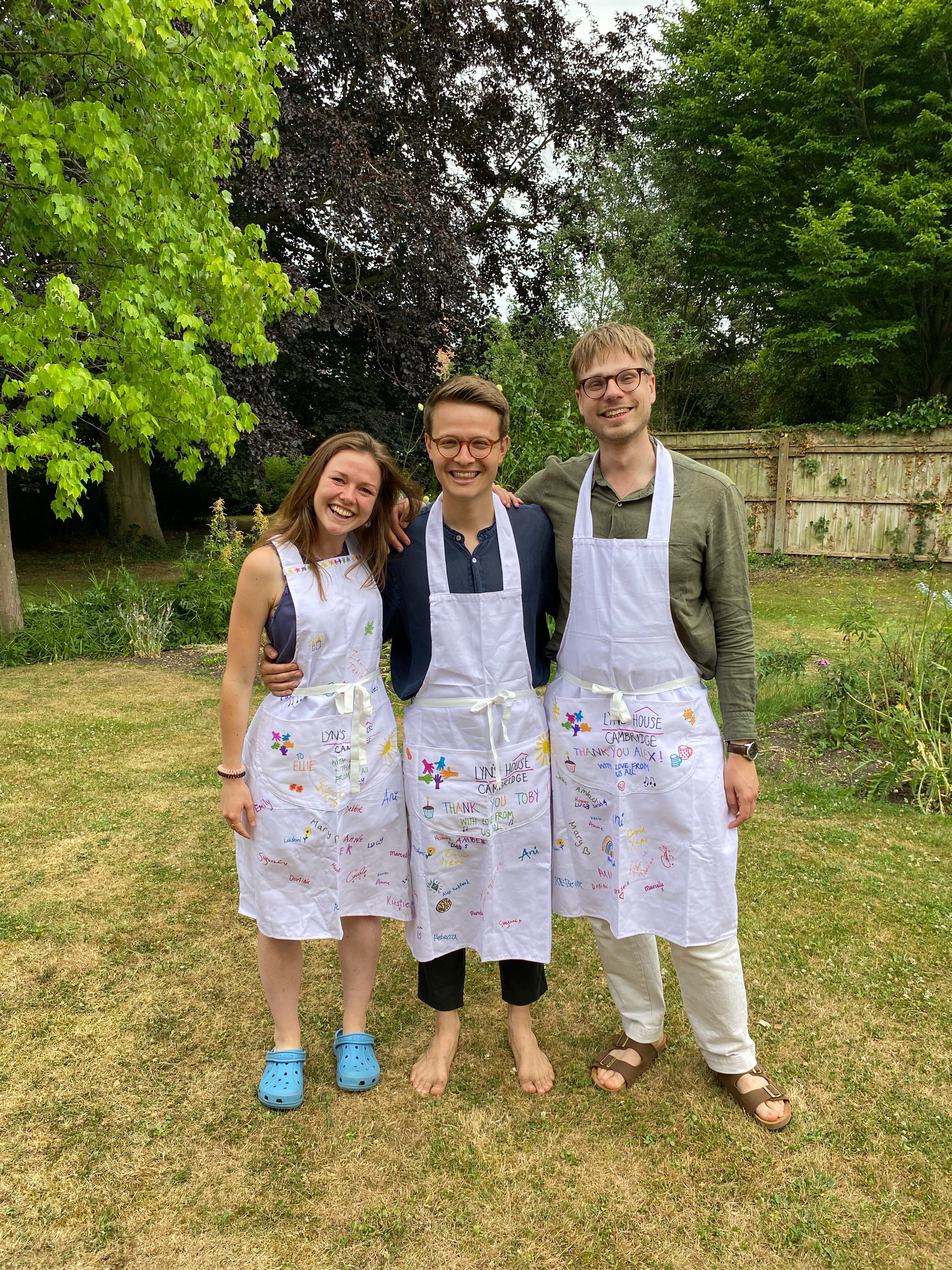 Three young adults wearing signed aprons