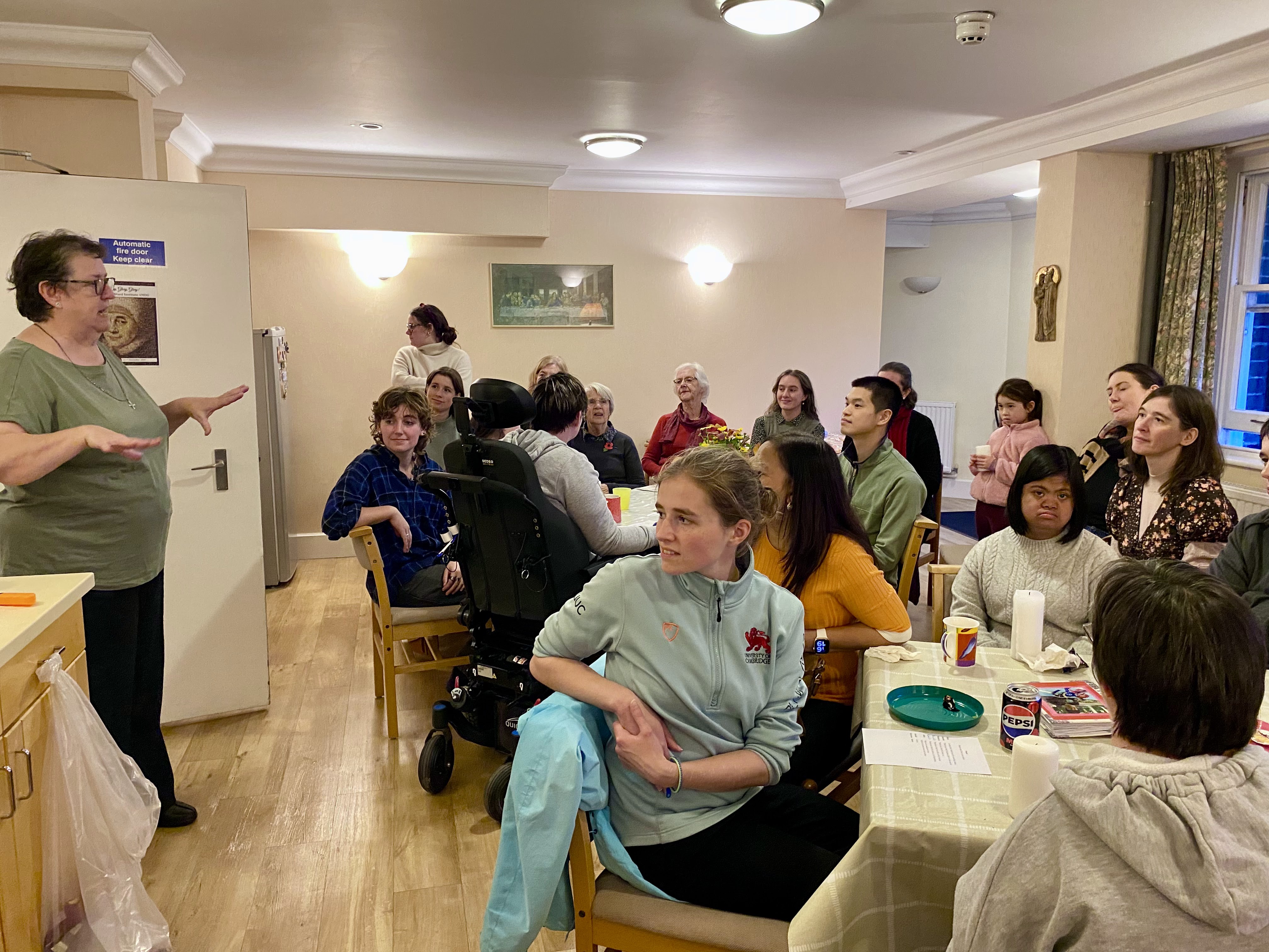 A large room full of people.  A woman is standing and speaking to everyone