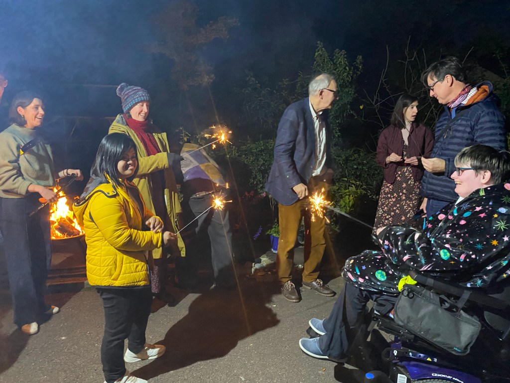 People in a dark, outdoor setting playing with sparklers